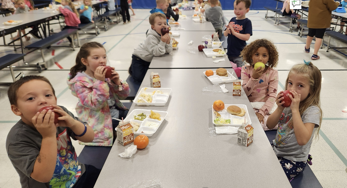 Kids crunching on apples in a school lunch room